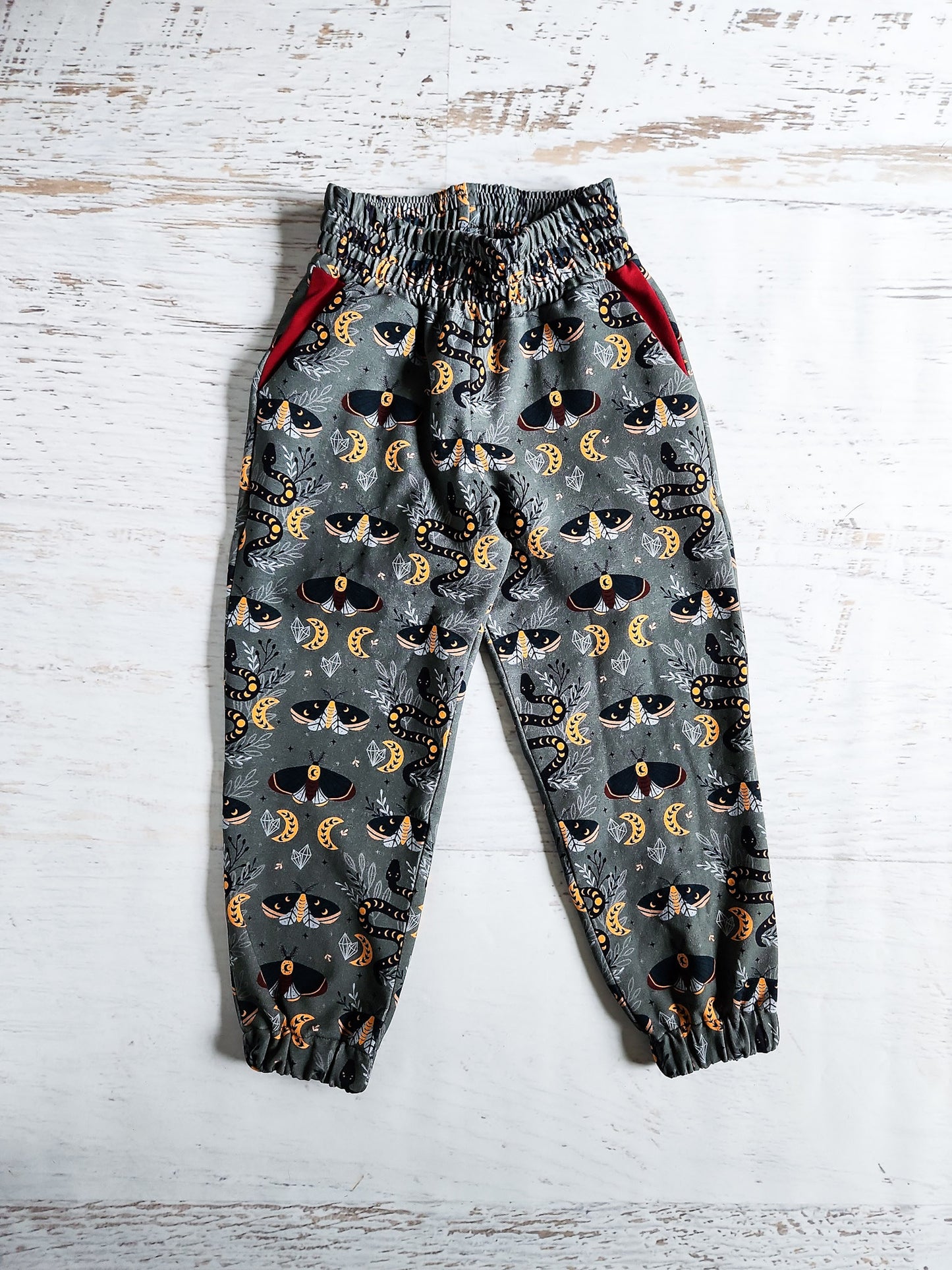 Mystical moths and snakes on green sweatpants, size 5.